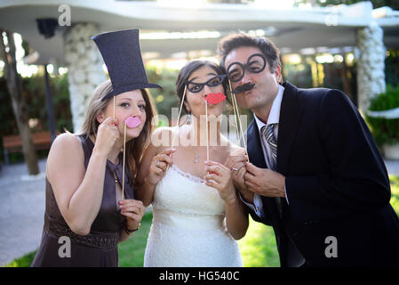 Just married couple playing with costumes and guests in wedding party Stock Photo