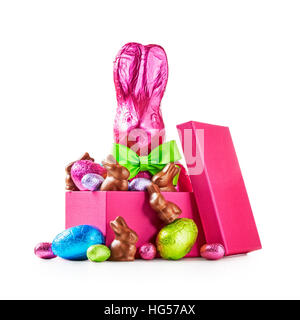 Gift box with chocolate easter eggs, rabbit with bow wrapped in pink foil, bunnies and colorful candies isolated on white background clipping path Stock Photo