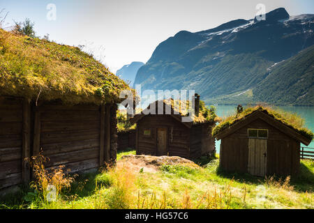 A view across Lovatnet Lake, a traditional Norwegian house sits in the foreground topped with sod roof. Stock Photo