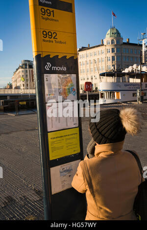 Denmark, Copenhagen, Nyhavn, Public Transport, woman looking at timetable on Harbour Bus 991 and 992 stop Stock Photo