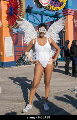 A woman with white angel wings & a mask poses for a photo at the Polar Bear Club annual winter swim in Coney Island Brooklyn NYC Stock Photo