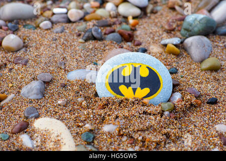 Paphos, Cyprus - November 22, 2016 Pebble with painted sign Batman lying on the beach with sand and stones. Stock Photo