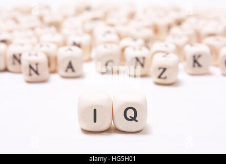 The word 'IQ' on the white  dice on a background of blurred letters. The concept of the mind, the intellect Stock Photo