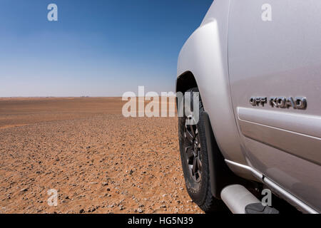 Close-up of a 4x4 off-road vehicle's left front side in the desert, with 'OFF ROAD' text on the door, large copy space and a Middle Eastern background Stock Photo