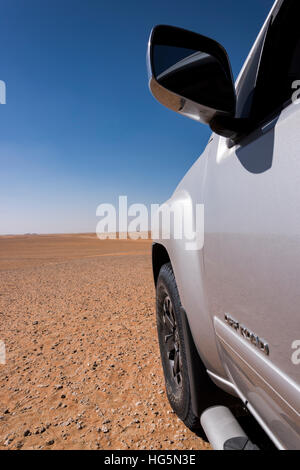 Close-up vertical view of a 4x4 off-road vehicle's left front side in the desert, with 'OFF ROAD' text on the door, large copy space, Middle East Stock Photo