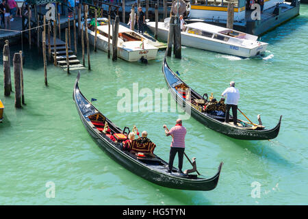 Venice,Italy-August 17,2014:two gondoliers lead tourists on a romantic trip on the canal in Venice during a summer day Stock Photo