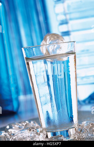 Ice cube falling into a glass of water Stock Photo