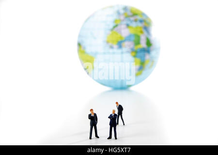 Three business executives in front of a globe Stock Photo