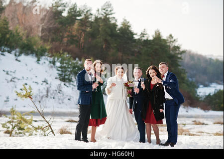 Best man with bridesmaids and newlyweds drinking champagne on frost winter wedding day. Stock Photo
