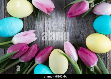 Tulips and colorful easter eggs in wooden background with copy space in center Stock Photo