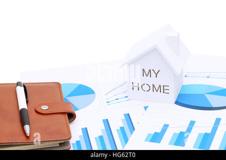 Miniature model of house on chart printed documents, leather notebook and pen Stock Photo