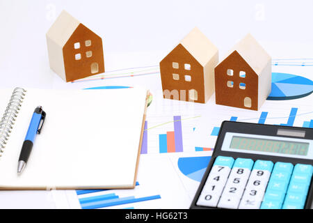 Miniature model of house on chart printed documents, notebook and pen Stock Photo