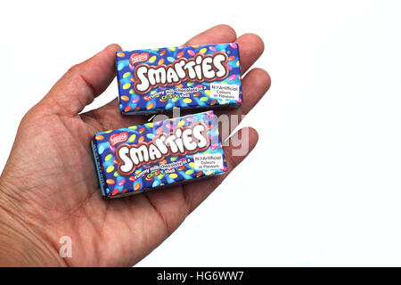 Close up of left hand holding Nestle Smarties isolated against white background Stock Photo