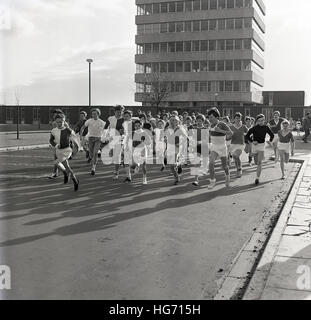 1960s, historical, group of school children taking part in a running competition, with Sixties built tower block in the distance. Stock Photo