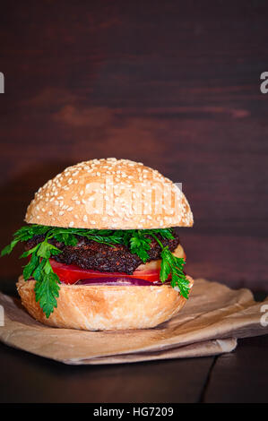 Hamburger with cutlet and vegetables served on paper, closeup Stock Photo