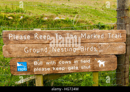 Sign at Balranald Nature Reserve on North Uist in Outer Hebrides warns of ground nesting birds and of a bull with cows in field. Stock Photo