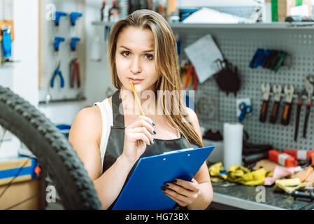 Charismatic technician taking notes in the workshop Stock Photo