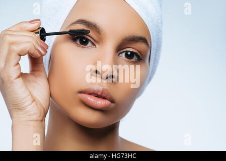 Charming pleasant woman putting on mascara Stock Photo