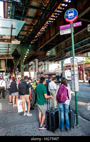 New York City,NY NYC Queens,Jackson Heights,Roosevelt Avenue,MTA bus stop,La Guardia,airport express bus Q70,adult,adults,man men male,woman female wo Stock Photo