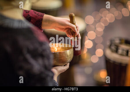 Woman playing on a tibetian singing bowl (shallow DOF; color toned image) Stock Photo