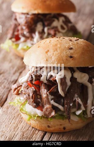 Pulled pork sandwich with vegetables and sauce close-up on the table. Vertical Stock Photo