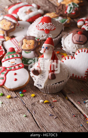 Christmas cupcakes and gingerbread cookies close-up on a wooden table. vertical Stock Photo