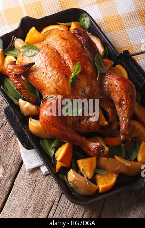 Delicious roast chicken with oranges and apples close-up in a pan. vertical Stock Photo