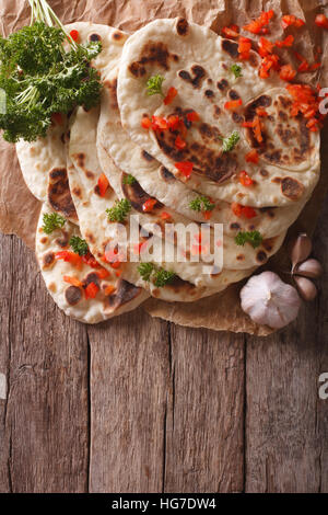 Indian Naan flat bread with garlic and herbs on the table. vertical top view Stock Photo