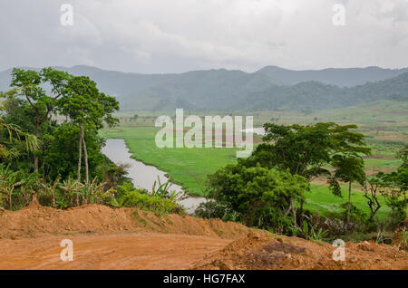 River and dirt road with mountains and lush vegetation at Ring Road in Cameroon, Africa Stock Photo