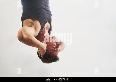 Fitness male is hanging upside down on horizontal bar Stock Photo