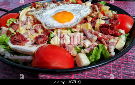 Plate of fried egg, chunks of bacon, sausage, cheese served with red tomato and lettuce Stock Photo