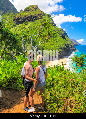 Hikers on the Kalalau Trail admire view of Hanakapiai Beach and the Na Pali Coast Stock Photo