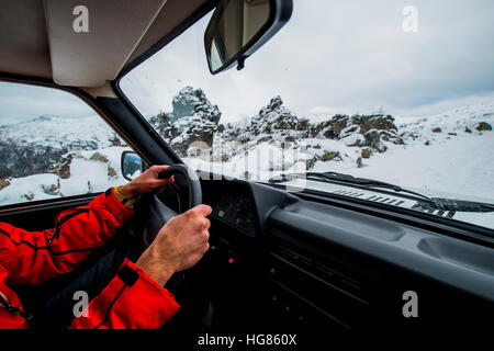 Man driving car on snow covered field Stock Photo