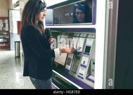 Woman inserting card in ATM machine Stock Photo