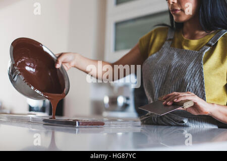 Midsection of woman pouring chocolate sauce in mold Stock Photo