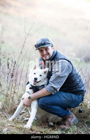 Portrait of man with dog crouching on field Stock Photo