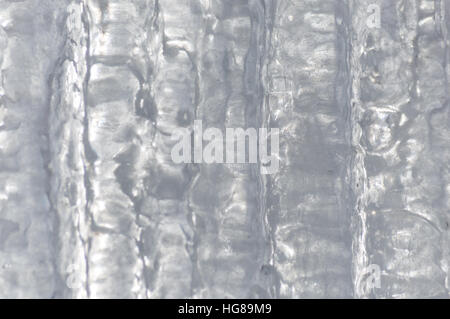 Ice background made of a number of icicles completely joined together. It has vertical patterns in the sunlight ice. Stock Photo