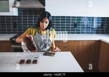 Woman pouring chocolate sauce in mold Stock Photo