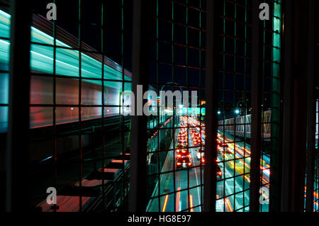 Blurred image of train on bridge over traffic at night Stock Photo