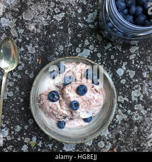 High angle view of blueberries and ice cream in bowl by jar and spoon on rock Stock Photo