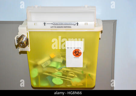 Photo of a locked yellow sharps container with used syringes, needles and scissors. Stock Photo