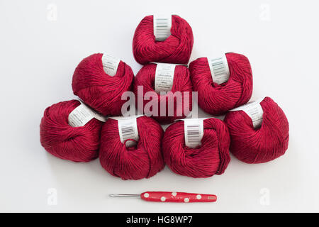 Eight red balls of wool with red novelty crochet hook on white background Stock Photo