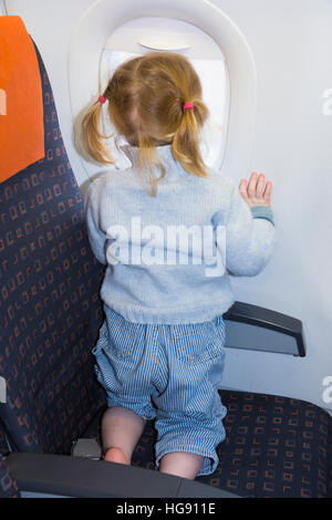 Child / toddler children age 2 on holiday vacation looking looks look out window flying on air plane / airplane aeroplane flight Stock Photo
