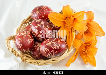 Wax decorated red Easter eggs in a wicker bowl Stock Photo