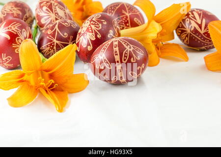 Wax painted red Easter eggs and orange flowers Stock Photo