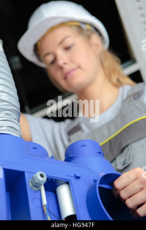 female worker operating machine in factory Stock Photo