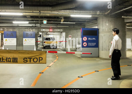 A parking attendant supervises cars in an underground car park in Tokyo, Japan. Stock Photo