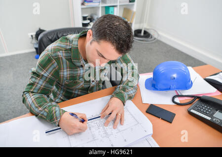 Man sat at desk working on blueprints Stock Photo