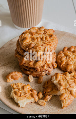 Salted crunchy peanut cookies freshly baked with crumbs and pieces on a wooden plate Stock Photo