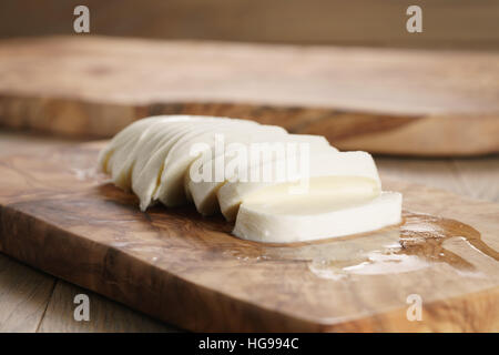 sliced ball of mozzarella cheese on wooden board Stock Photo